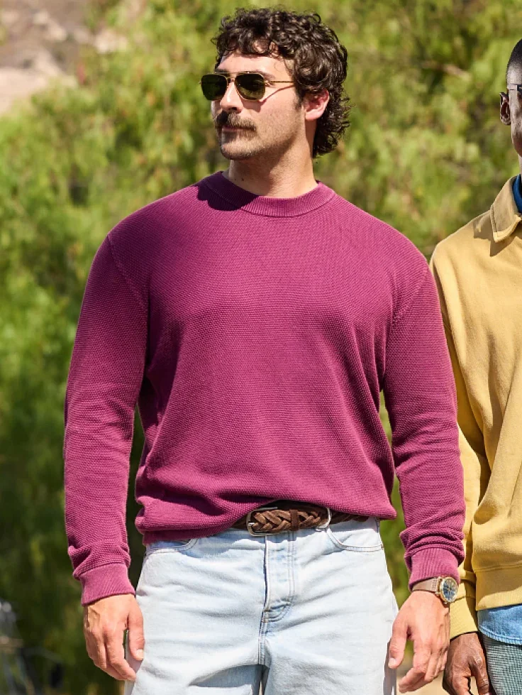 A man in sunglasses wears a plum crewneck sweater