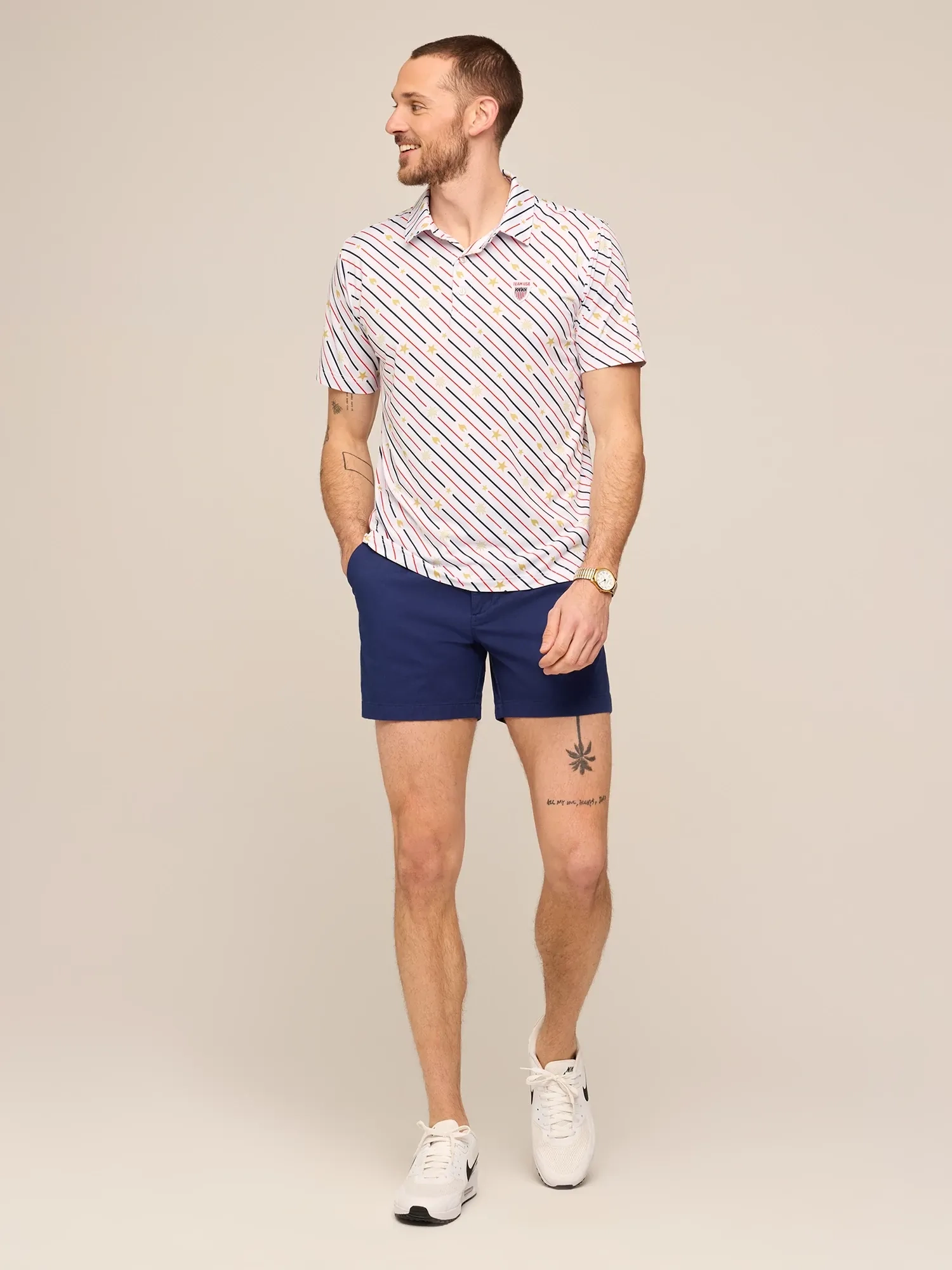 A man in a white printed polo and navy shorts