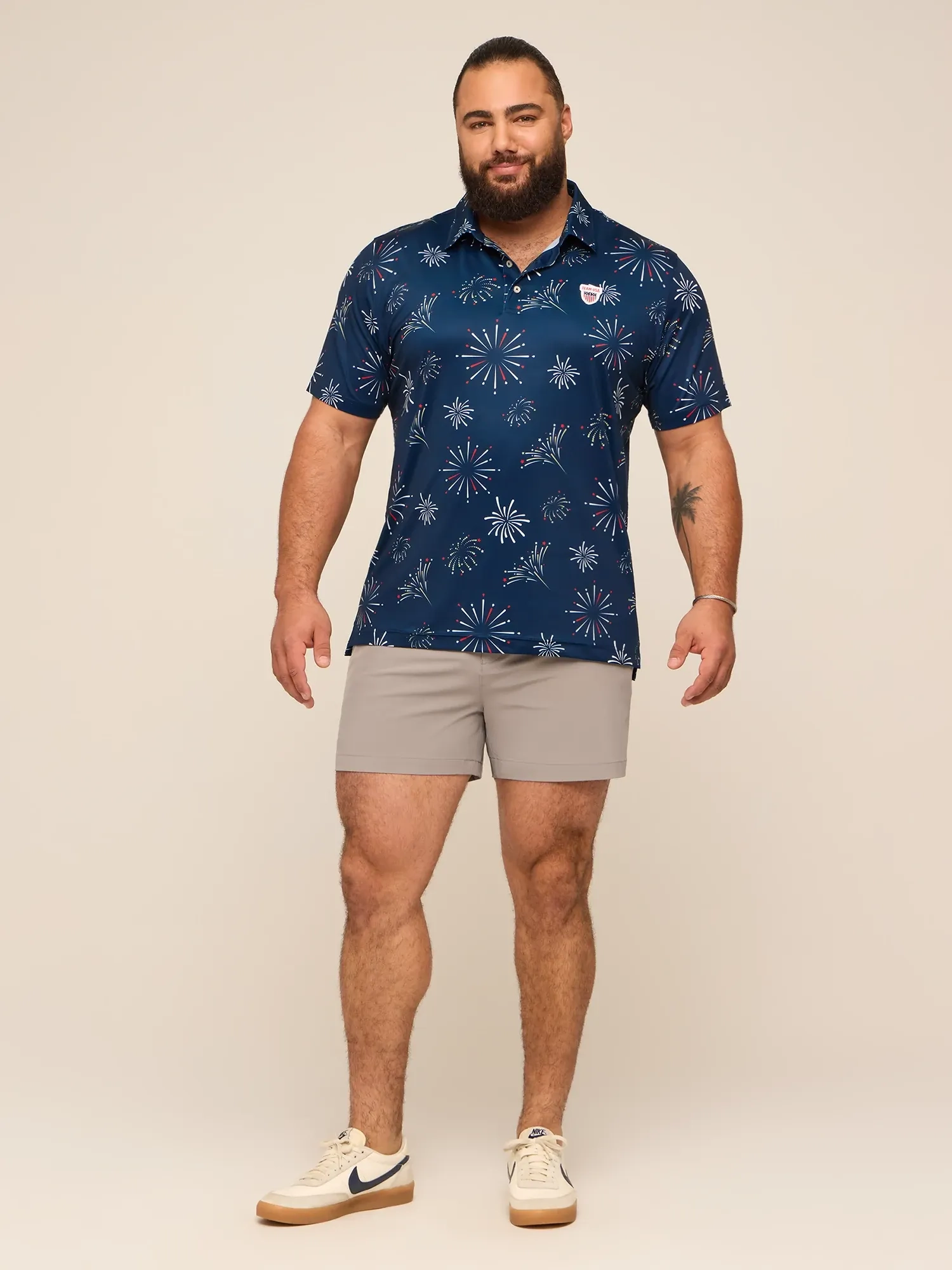 A man in a navy printed polo and gray shorts